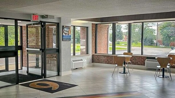 Eine Lobby mit einem Hinweisschild für den Ausgang, einem Empfangsbereich und einer Sitzecke mit Stühlen.