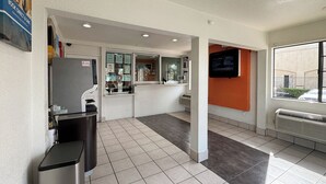 A clean, modern interior with a reception desk, a trash bin, and a window providing a view of the outside.