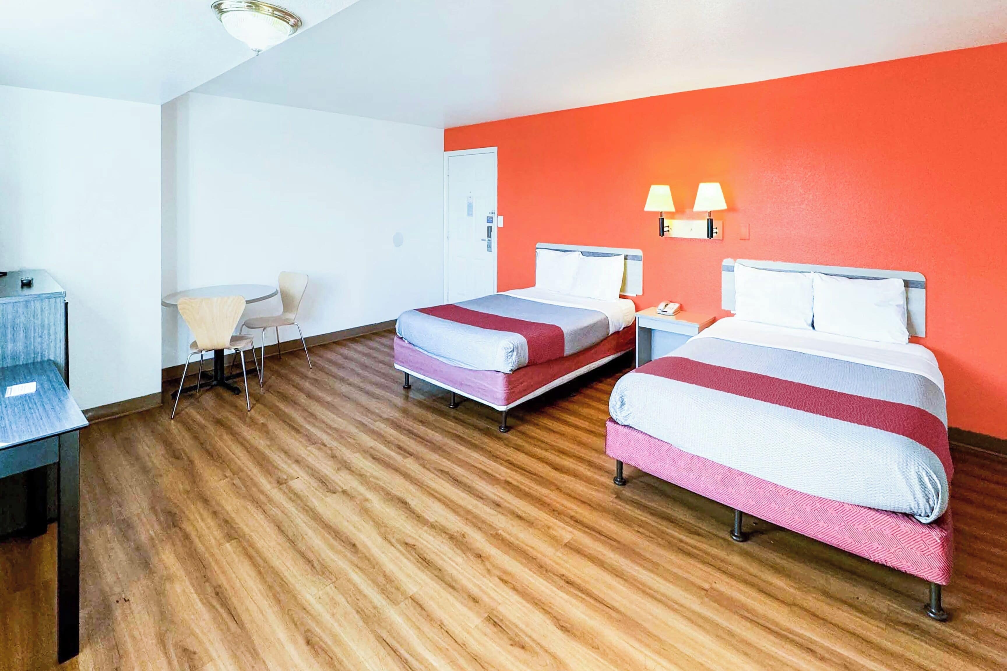 Habitación de hotel con dos camas, un escritorio, una silla y una mesita.