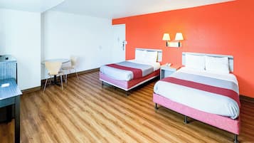 Habitación de hotel con dos camas, un escritorio, una silla y una mesita.