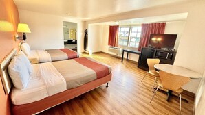 A hotel room with two beds, a desk, a chair, a TV, and a window with curtains.