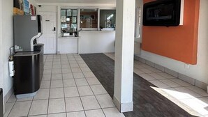 A modern kitchen with a refrigerator, sink, and a television mounted on the wall.
