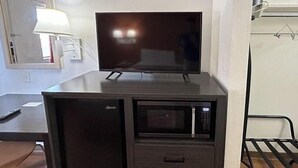 A compact kitchenette with a microwave, a small refrigerator, and a flat-screen TV.