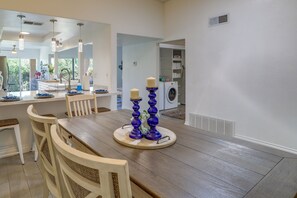 Un coin repas avec une table en bois, des chaises blanches et un porte-bougie bleu.