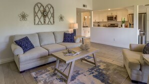 A living room with a sofa, coffee table, and decorative wall art. - Palm Desert Vacation Rental w/ Community Pool! (Palm Desert)