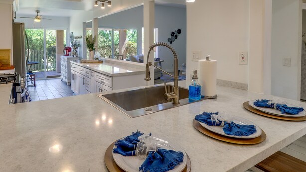A modern kitchen with a large island, stainless steel sink, and pendant lighting. - Palm Desert Vacation Rental w/ Community Pool! (Palm Desert)