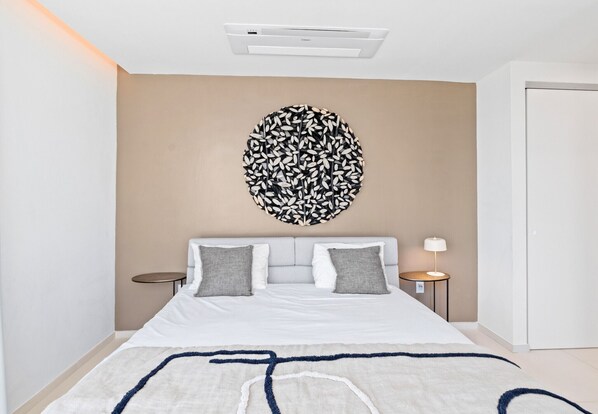 A bedroom with a bed, a round wall decoration, a bedside table, and a lamp.