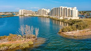 A waterfront hotel with multiple buildings, a clear blue sky, and calm water.