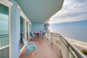A balcony with a table and chairs, overlooking a beach. - Beachfront Gulfport Vacation Rental w/ Balcony! (Gulfport)