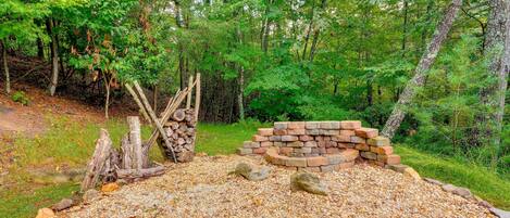 A forested area with a gravel path, wooden logs, and a brick structure.