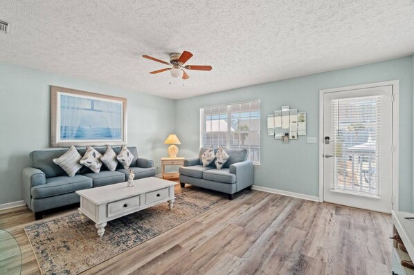 A living room with two grey sofas, a white coffee table, and a ceiling fan.