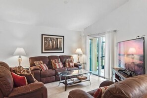 Ein Wohnzimmer mit einer Sofagarnitur, einem Couchtisch und einem Flachbildfernseher.