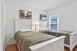 A room with two beds, a nightstand, a lamp, and two framed pictures on the wall. - Beautiful one story w/ pool home. Near Disney! (Kissimmee)