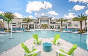 A swimming pool with lounge chairs and a covered area with palm trees.