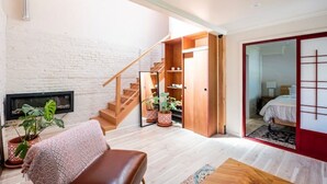 A compact living space with a staircase, a sofa, a coffee table, and potted plants. - Guesthouse, Urban Oasis, 2b/2bth (Berkeley)
