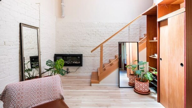 A spacious living area with a staircase, wooden flooring, and potted plants. - Guesthouse, Urban Oasis, 2b/2bth (Berkeley)