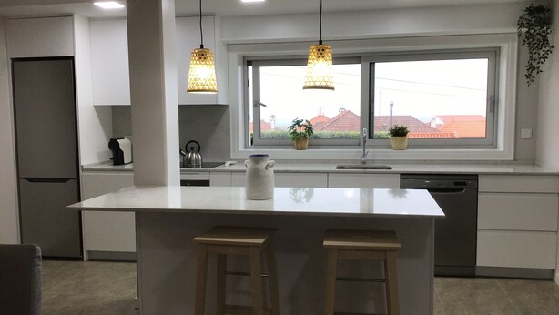 A modern kitchen with a central island, pendant lights, a window with a view, and a sink. - oceanview,  restaurants, beach , surrounded by mountains ,rivers and nature.  (Viana do Castelo)