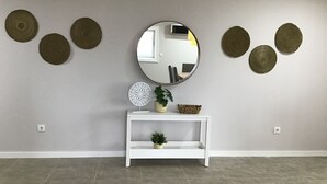 A room with a white console table, a round mirror, and decorative woven circles on the wall. - oceanview,  restaurants, beach , surrounded by mountains ,rivers and nature.  (Viana do Castelo)