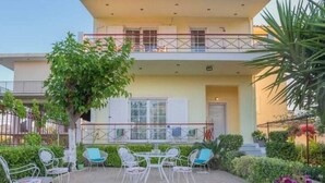 Ein zweistöckiges Gebäude mit Balkon, Sitzbereich im Freien und Topfpflanzen.