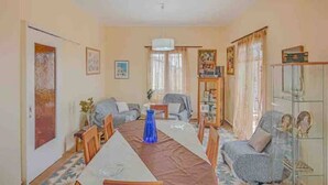 Una sala de estar con una mesa de comedor, sillas, un sofá y un aparador de vidrio.