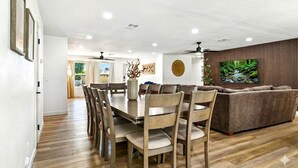 Uma sala de estar com uma mesa e cadeiras de madeira, um sofá e uma televisão.