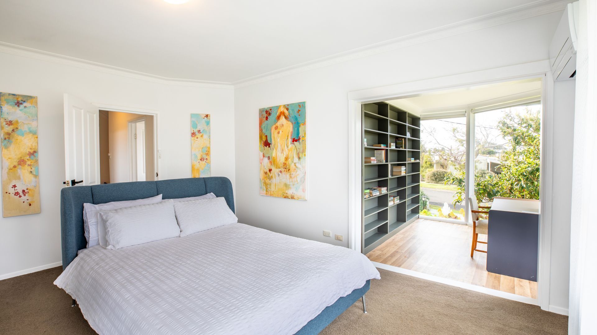 Une chambre à coucher avec un lit, une bibliothèque et une vue sur l’extérieur.