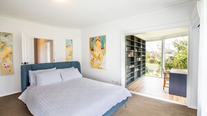 Ein Schlafzimmer mit einem Bett, einem Bücherregal und Blick ins Freie.