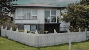 A two-story house with a white picket fence, a balcony, and a garage.