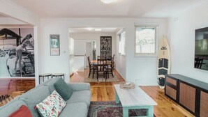 Ein modernes Wohnzimmer mit grauem Sofa, einem Couchtisch und einem Surfbrett an der Wand.