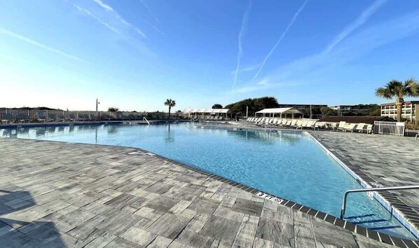 A swimming pool with lounge chairs and a wooden deck.