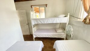 A small, clean room with two bunk beds, a white door, and a window with curtains. - Hostal Playa Azul (Corinto)