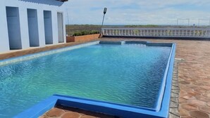 A rectangular swimming pool with a blue edge, surrounded by a tiled patio. - Hostal Playa Azul (Corinto)