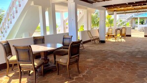An outdoor patio area with a round table and chairs, a staircase, and a view of the surrounding landscape. - Hostal Playa Azul (Corinto)