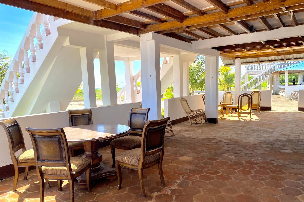 An outdoor patio area with a round table and chairs, a staircase, and a view of the surrounding landscape.