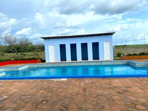 A pool area with a tiled floor and a building with multiple doors.
