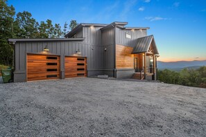 Ein modernes, zweistöckiges Haus mit Garage, überdachter Veranda und Bergblick.