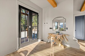 Ein modernes Interieur mit Holzboden, einem großen Spiegel und einer Schiebeglastür.