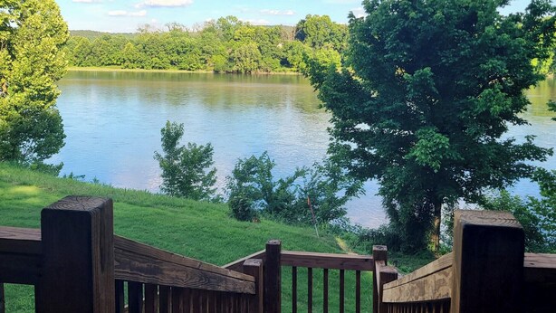 A wooden deck overlooking a lake with trees and a clear sky. - Beautiful Secluded Cabin on the White River (Calico Rock)