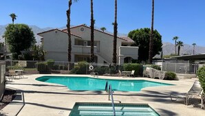 A pool area with two swimming pools, a diving board, and lounge chairs.
