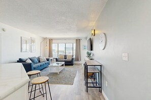A modern living room with a sofa, coffee table, and a dining area with a table and chairs.