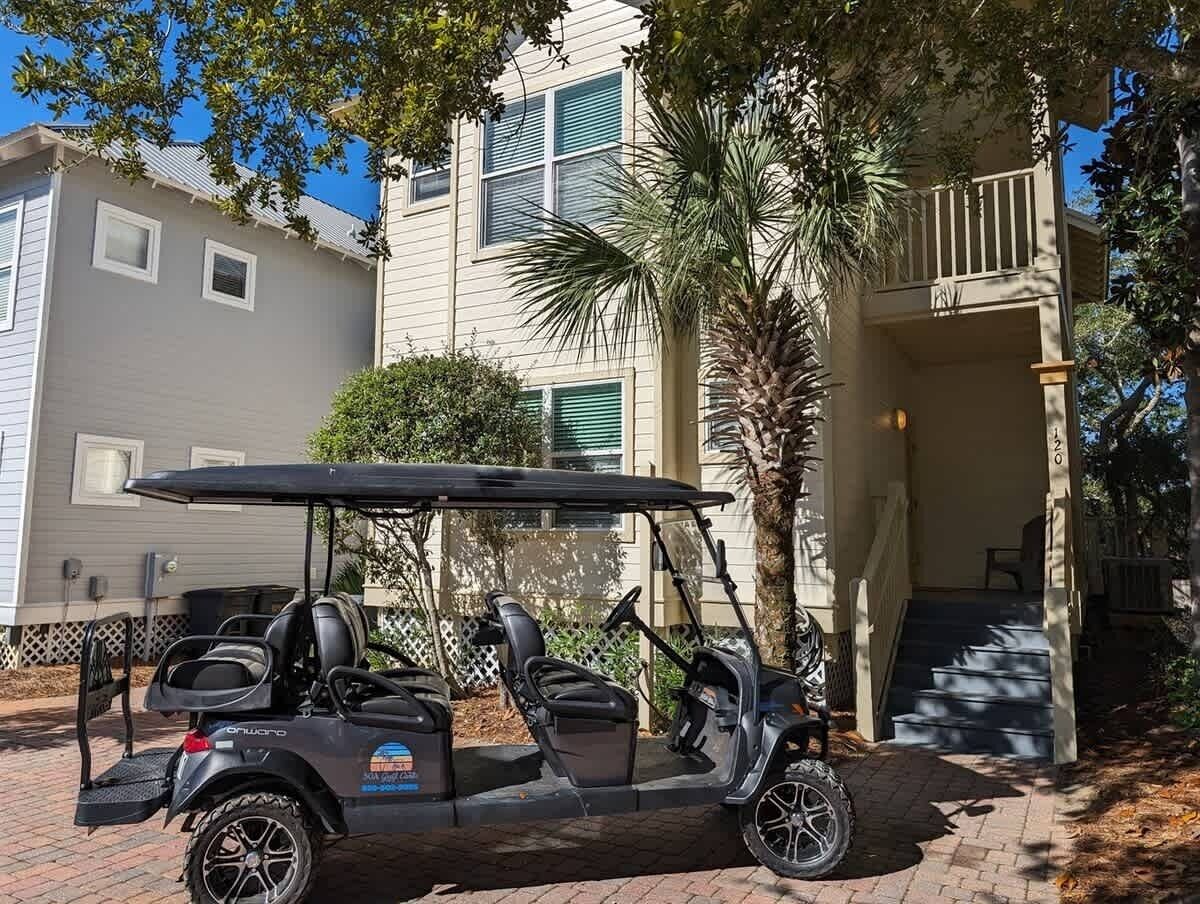 Carro de golf estacionado frente a una casa con porche cubierto y una escalera que lleva a la entrada.