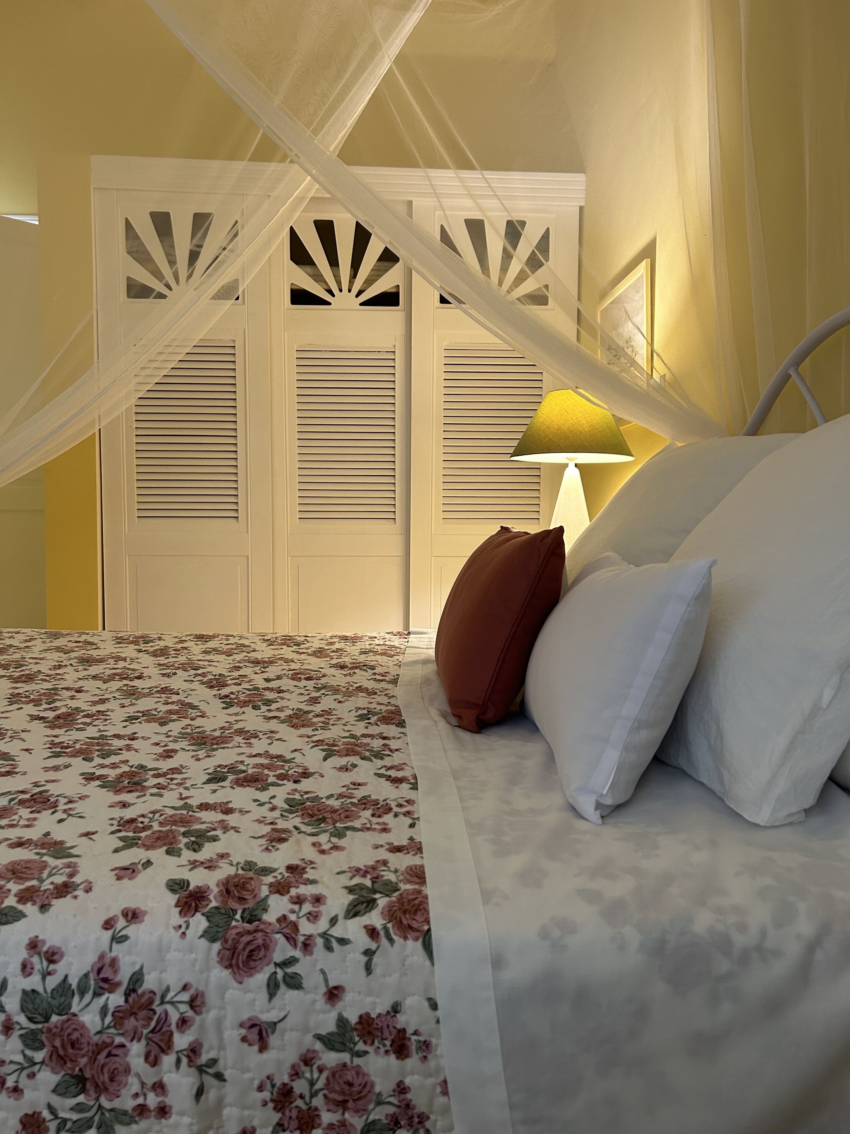 Une chambre à coucher avec une couvre-lit à motifs floraux, un lit à baldaquin et une table de chevet avec une lampe.