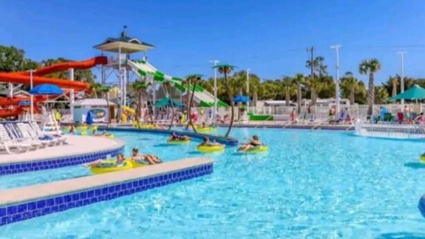 En swimmingpool med vandrutsjebaner og liggestole.