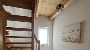 A wooden staircase leading to a loft area with a window and a painting on the wall. - Wohnung Carmen (Bad Rappenau)