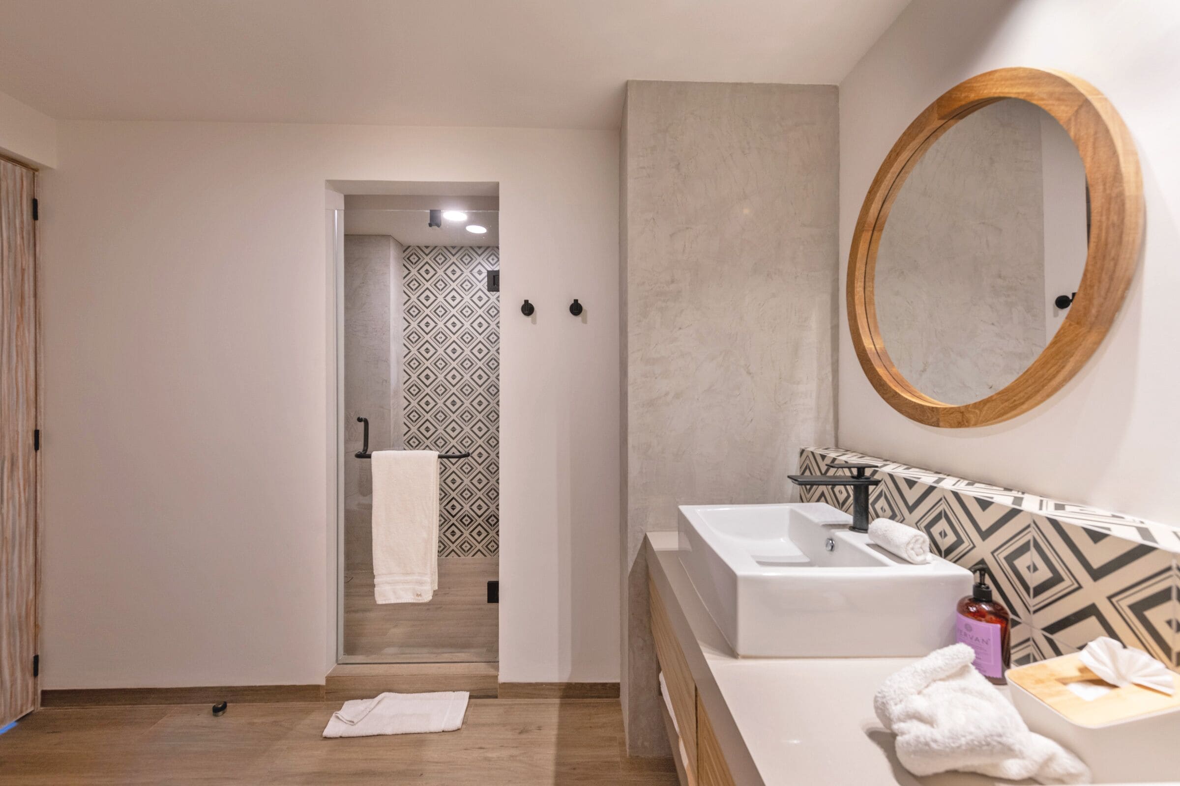 A modern bathroom with a large mirror, a sink, and a shower area.