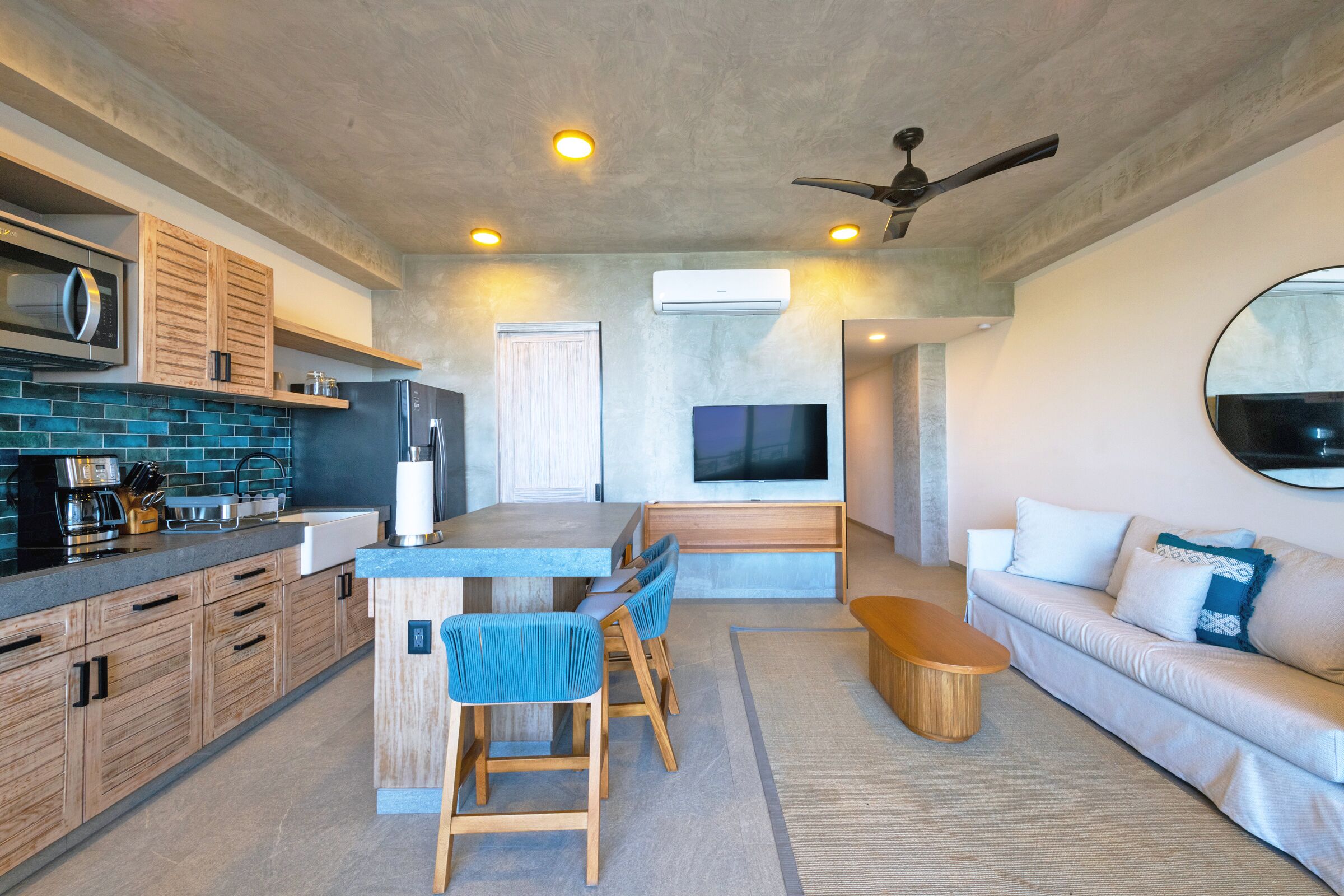 A modern kitchen with wooden cabinets, a built-in microwave, and a large island with bar stools.