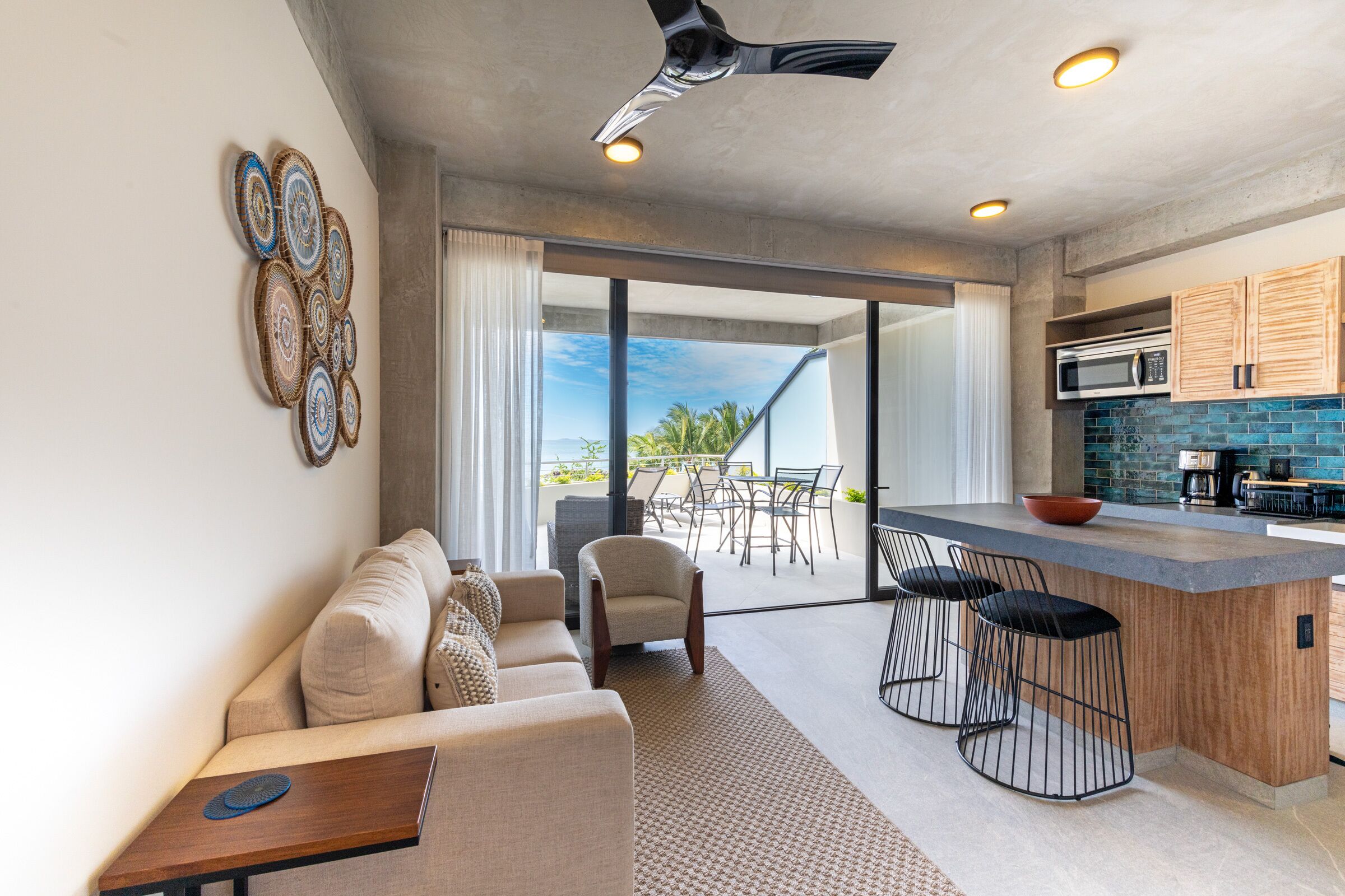 A modern kitchen with a large island, bar stools, and a dining area with a view.