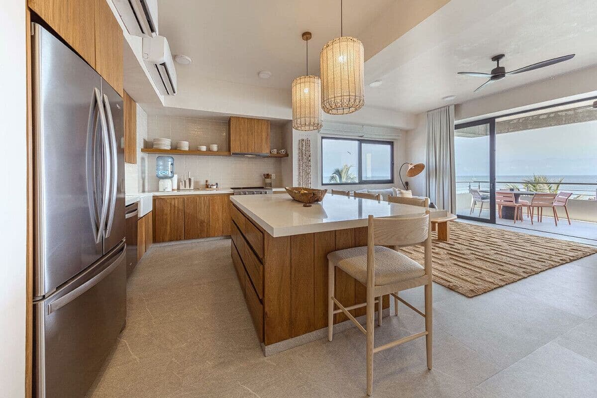 Una cocina moderna con una isla grande, electrodomésticos de acero inoxidable y vista al océano.