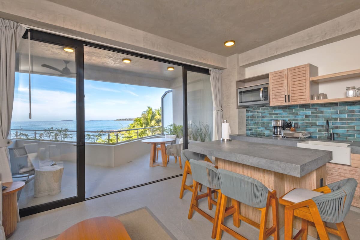 Una cocina moderna con una isla grande, taburetes de bar y vista al océano.