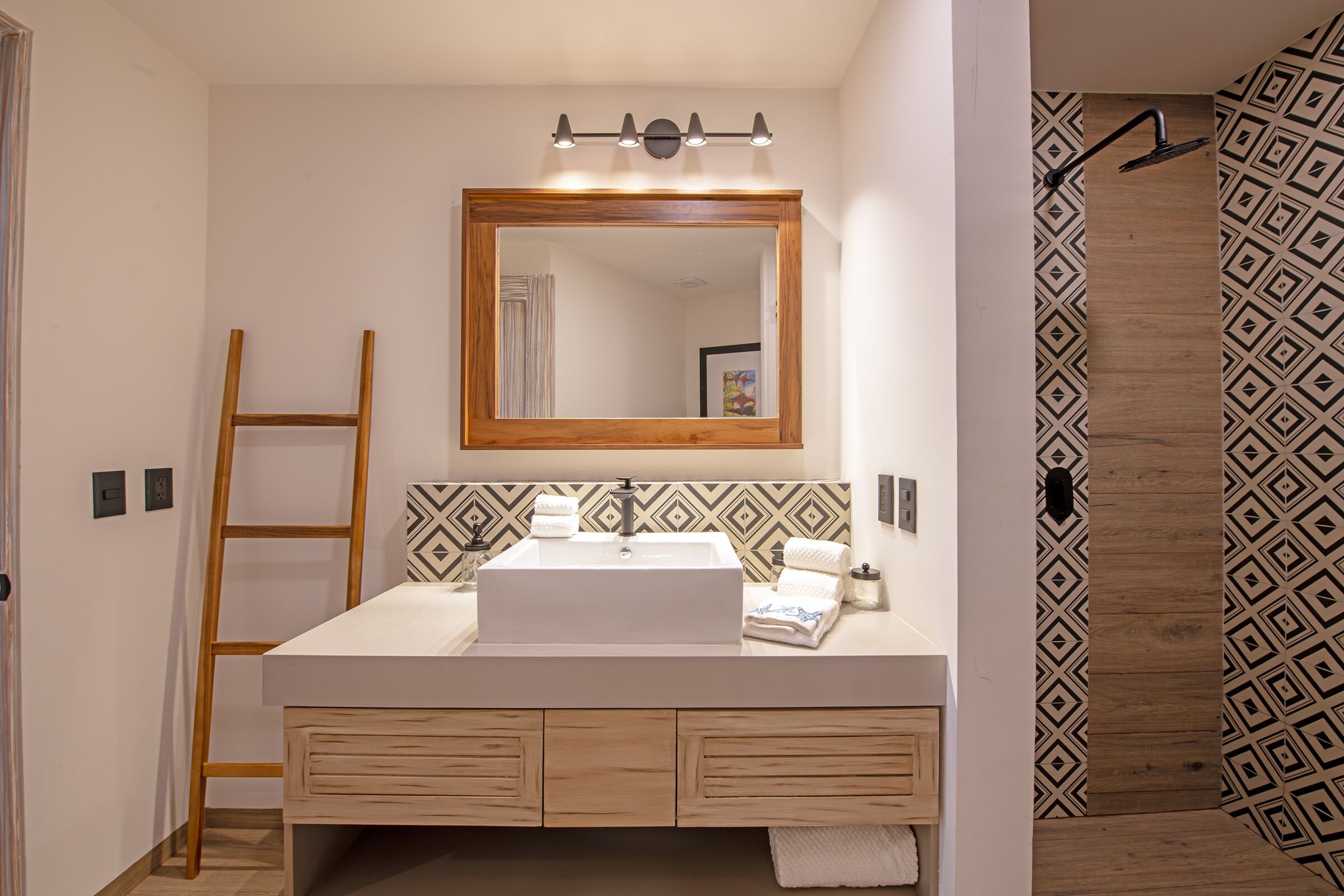 Une salle de bain avec un meuble-lavabo en bois, un grand miroir et des carreaux à motifs.